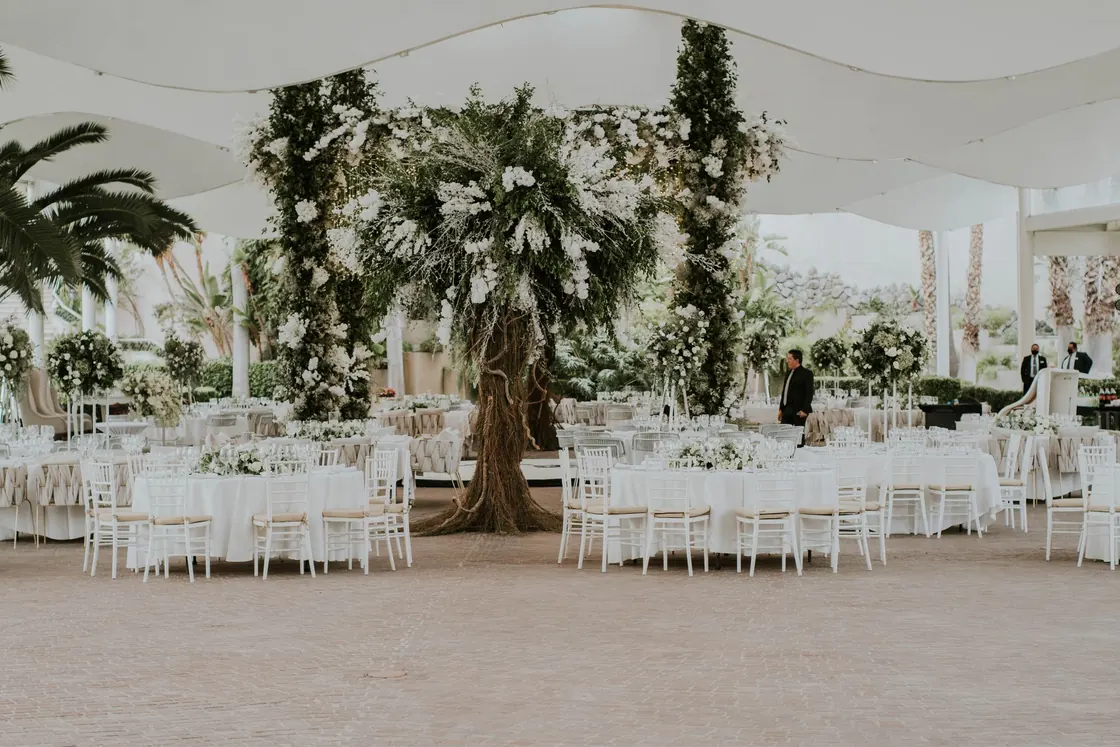 White tables and floral arrangements beneath an outdoor canopy