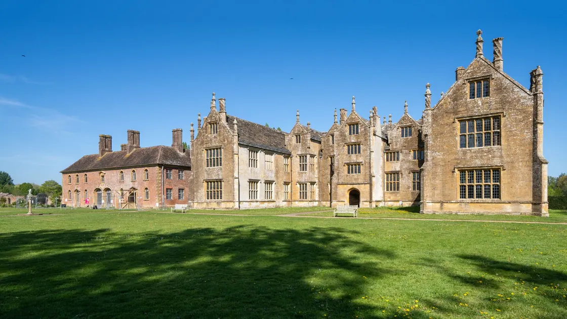 A historic English manor house and its sunlit lawn