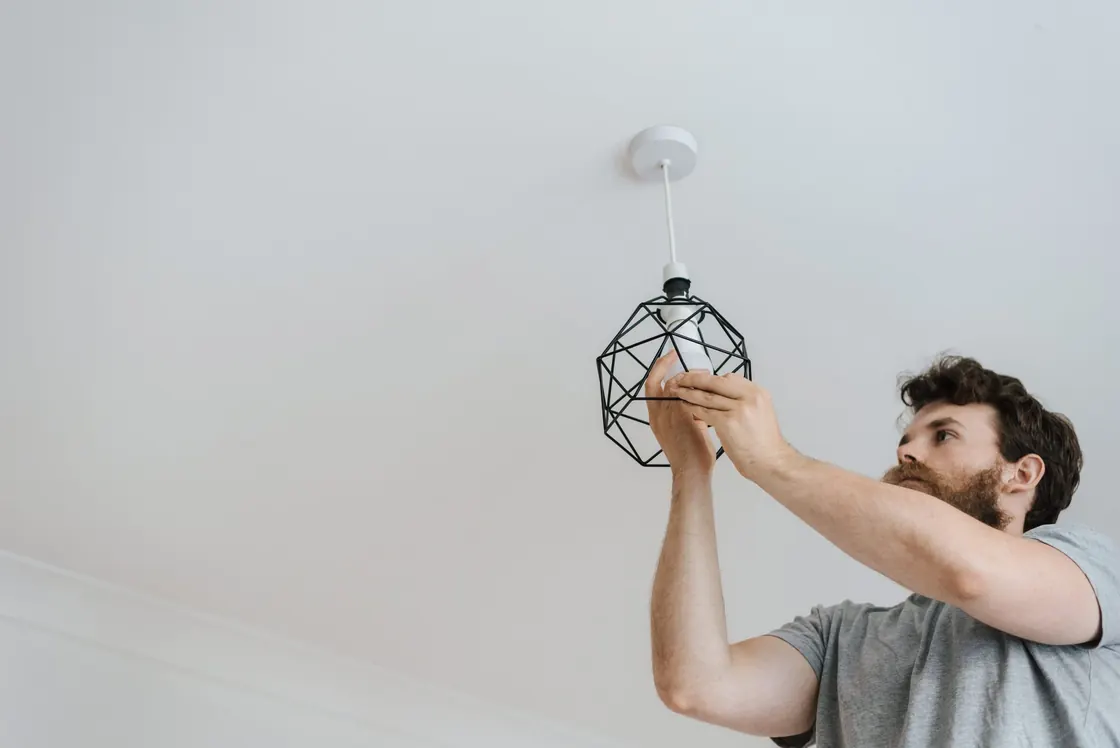 A worker fitting a bulb into a geometric ceiling light