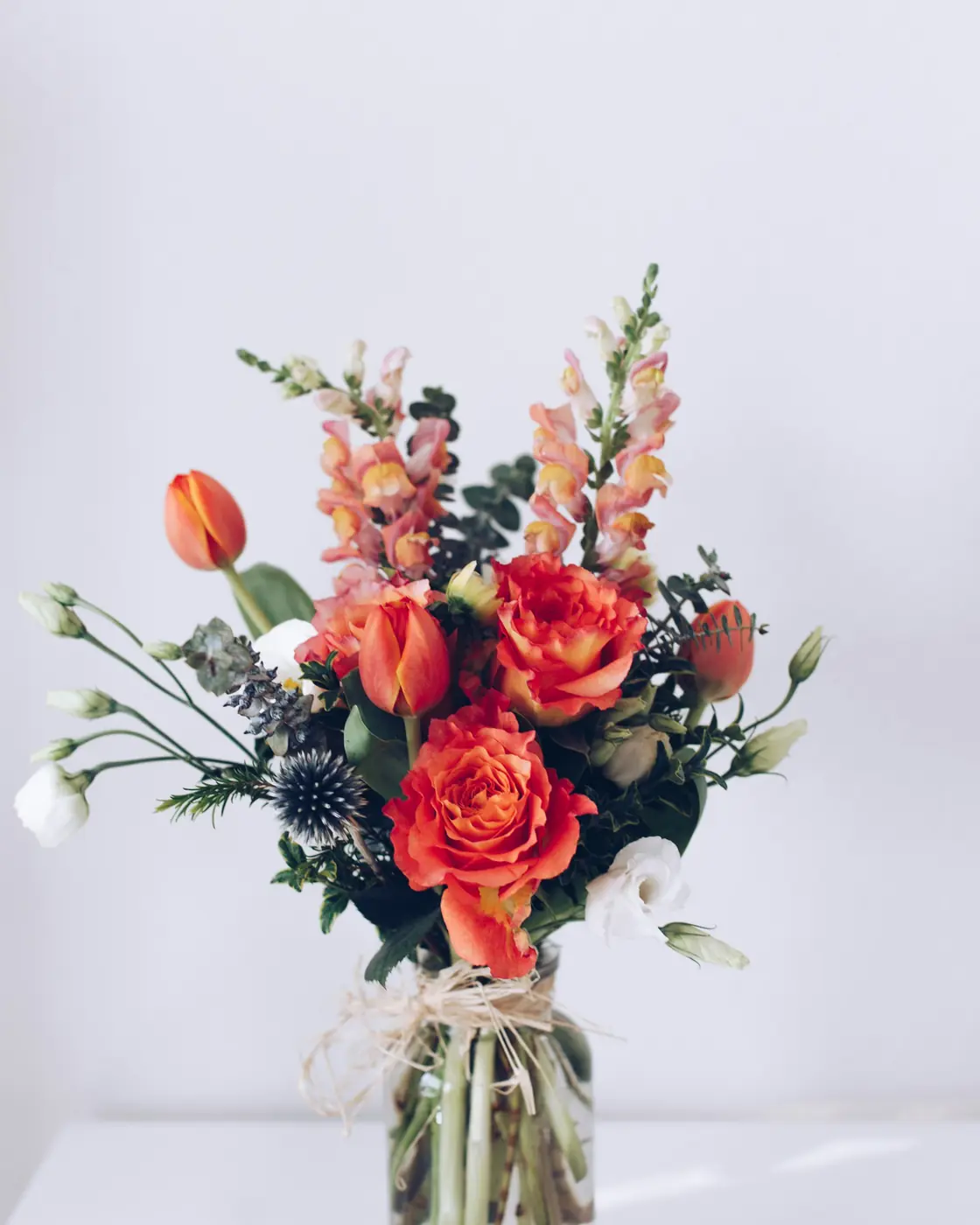 A bright arrangement of orange, pink and white flowers in a glass vase