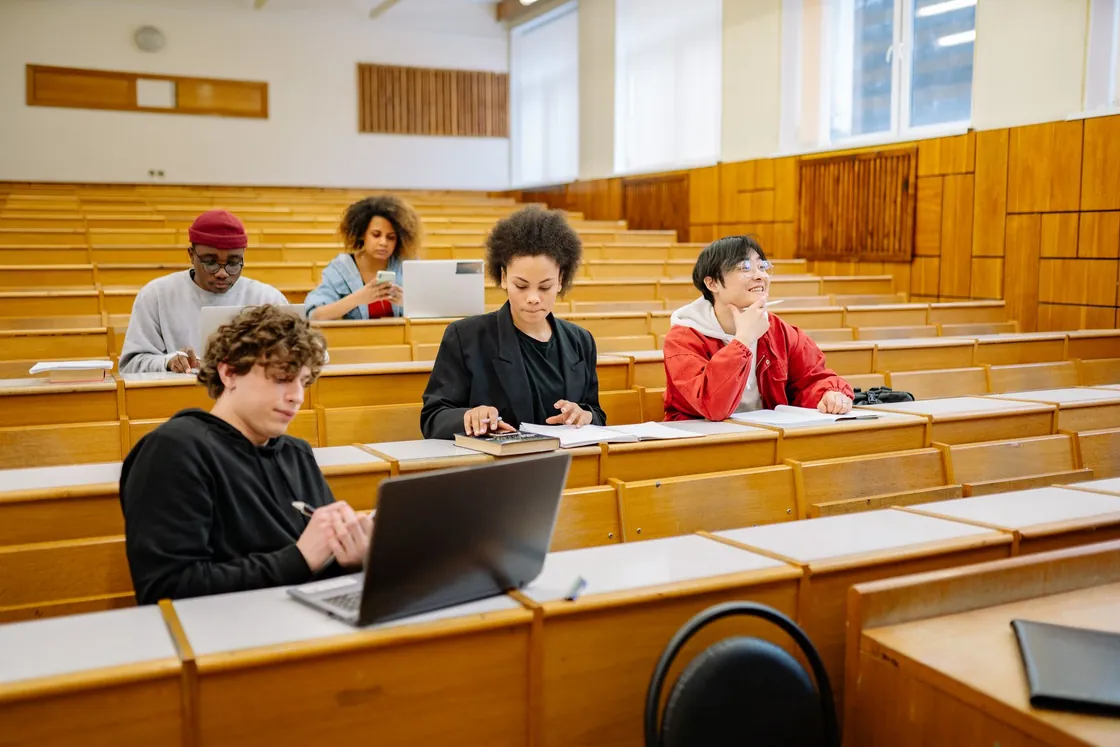 Adult learners seated at desks, using notebooks and laptops