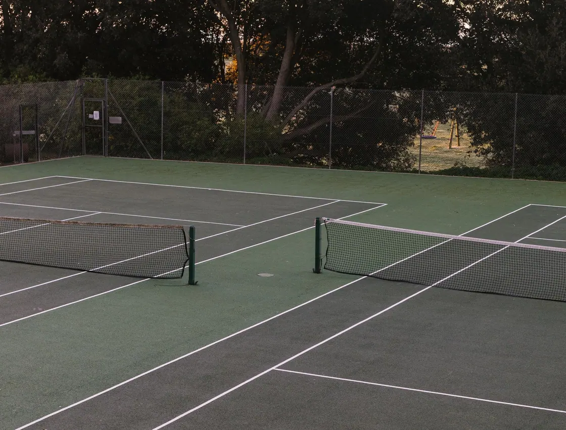 An outdoor tennis court surrounded by trees