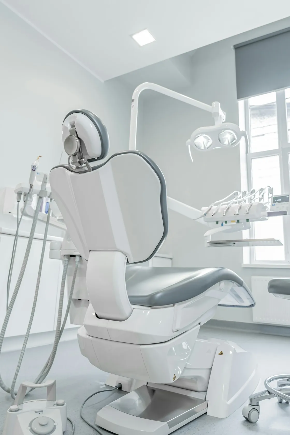 A white dental chair and examination equipment beside a window