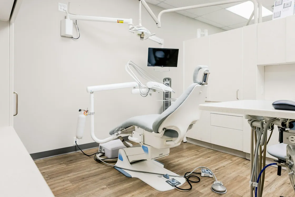 A dental treatment room with a chair, monitor and clinical equipment