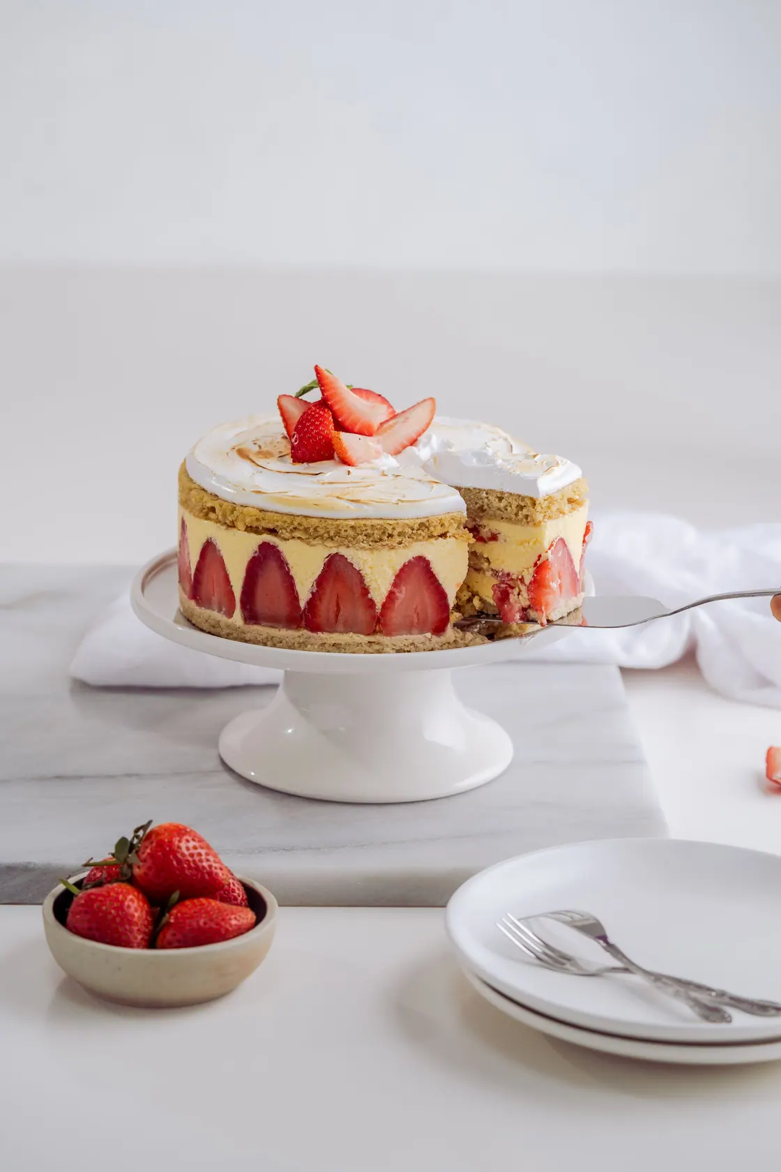 A strawberry-topped celebration cake on a stand