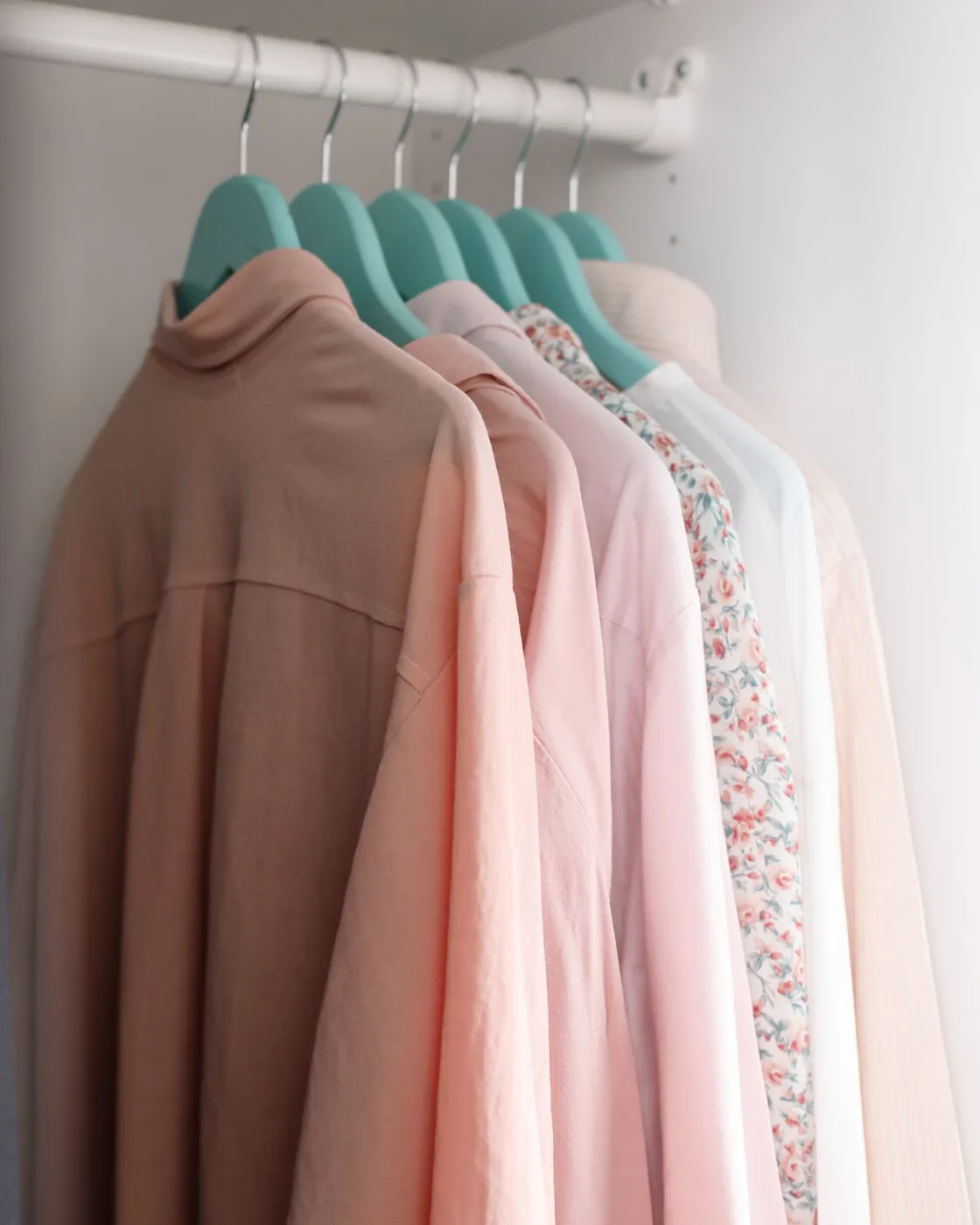 Pastel shirts on mint-coloured hangers in a wardrobe