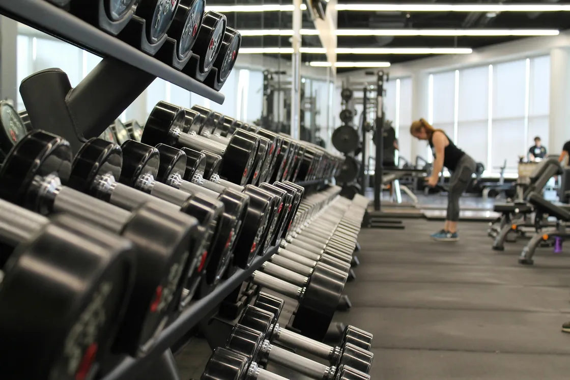 A wide gym floor with exercise machines and free-weight equipment