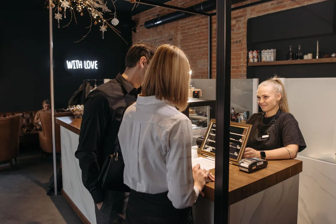 Customers at a café counter speaking with a member of staff