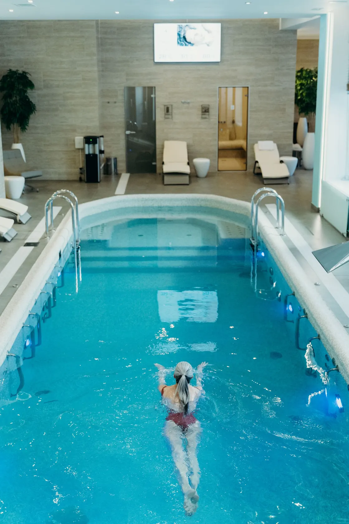 A swimmer in an indoor pool with surrounding seating