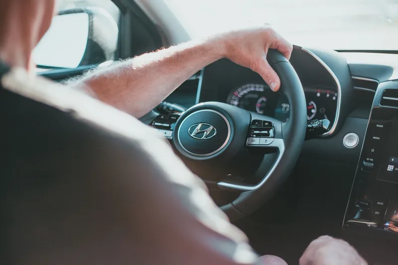 View from the passenger side of a person holding a Hyundai steering wheel