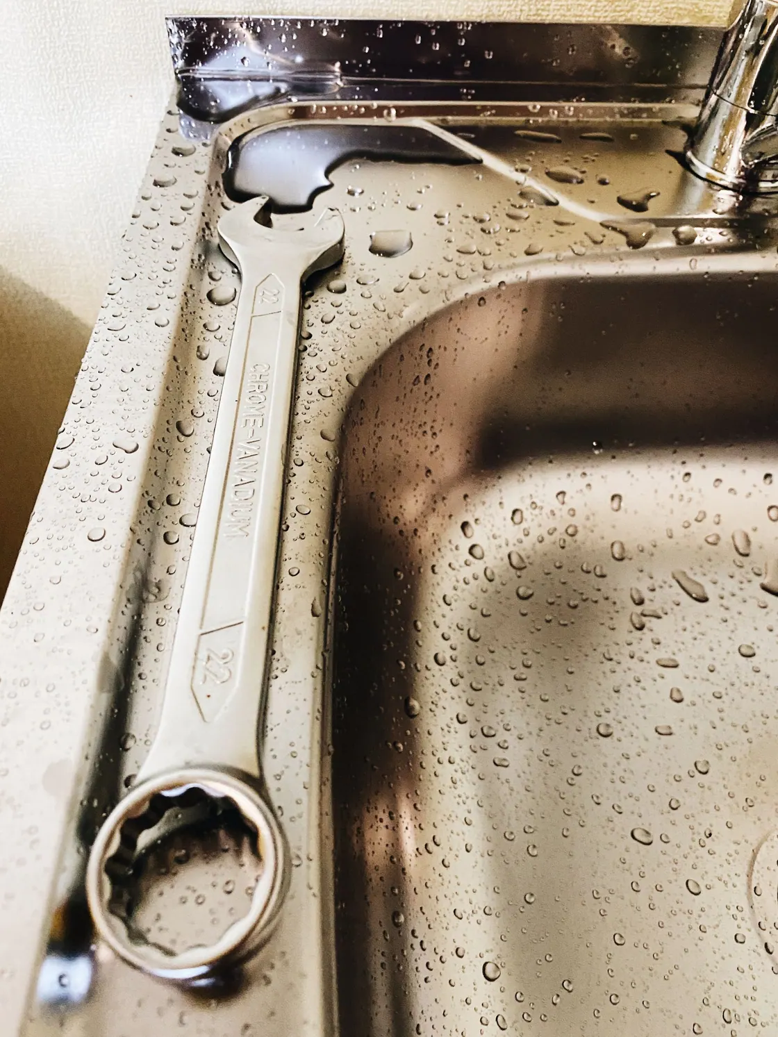 A wrench resting on a stainless steel sink