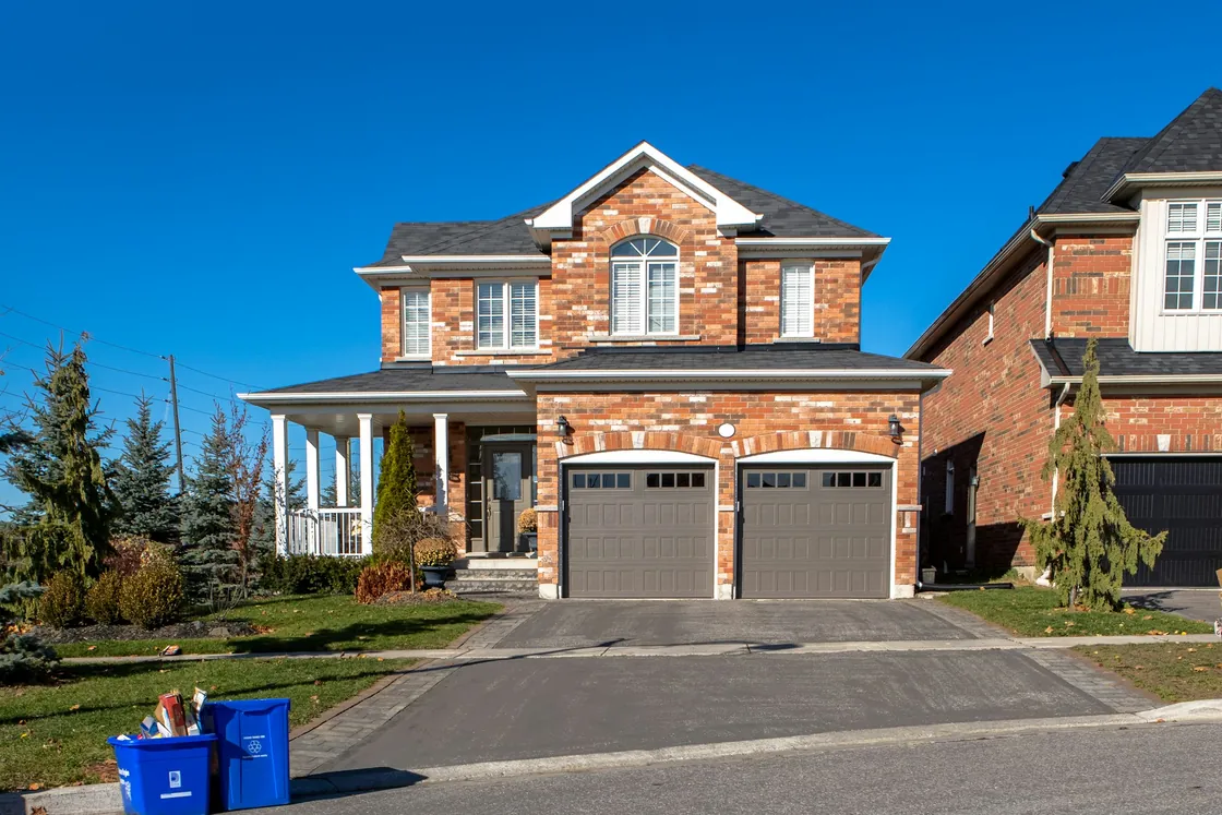 Red brick detached house with a garage, driveway and front lawn