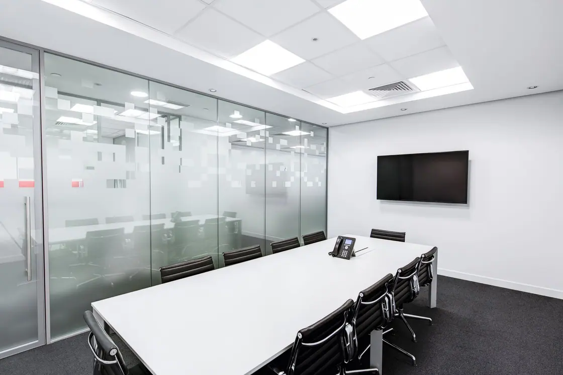 A glass-walled meeting room with a long table