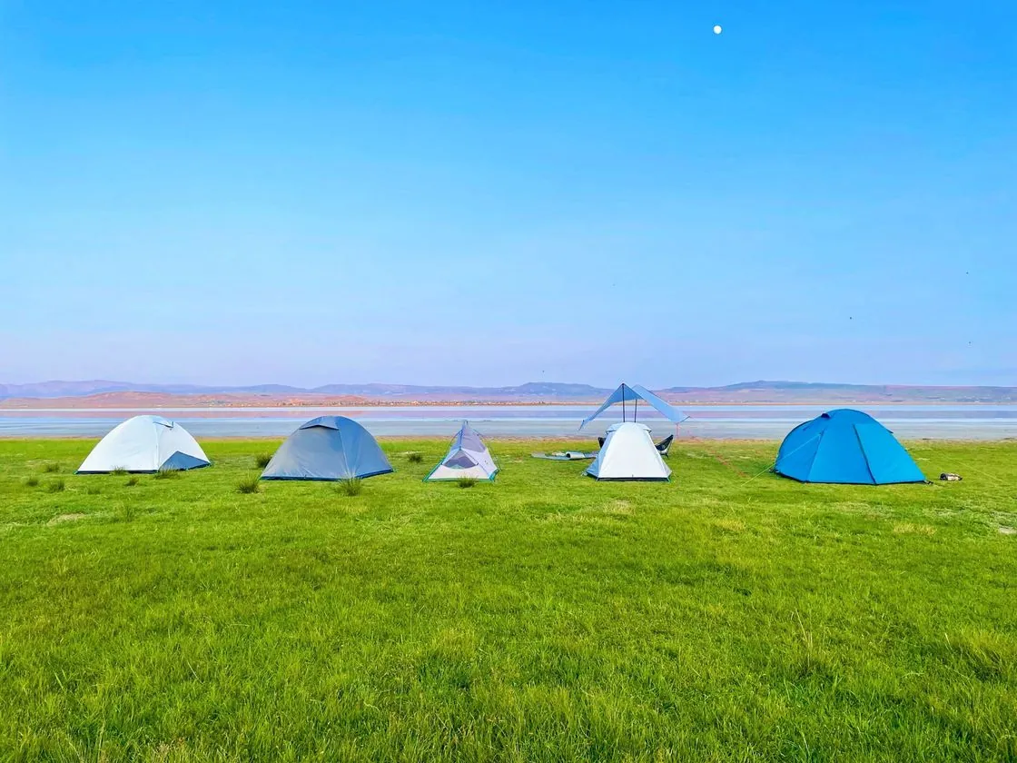 Colourful tents set on grass beside a lake