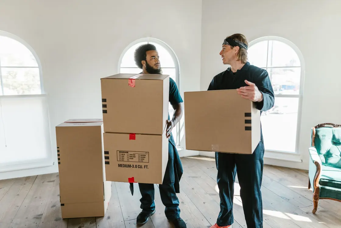 Movers carrying cardboard boxes inside a home
