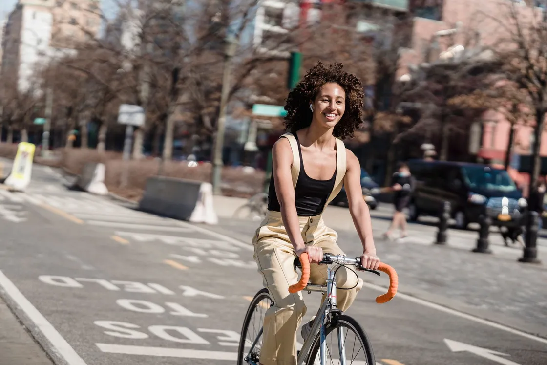 Woman riding a drop-bar bicycle along a sunny city street