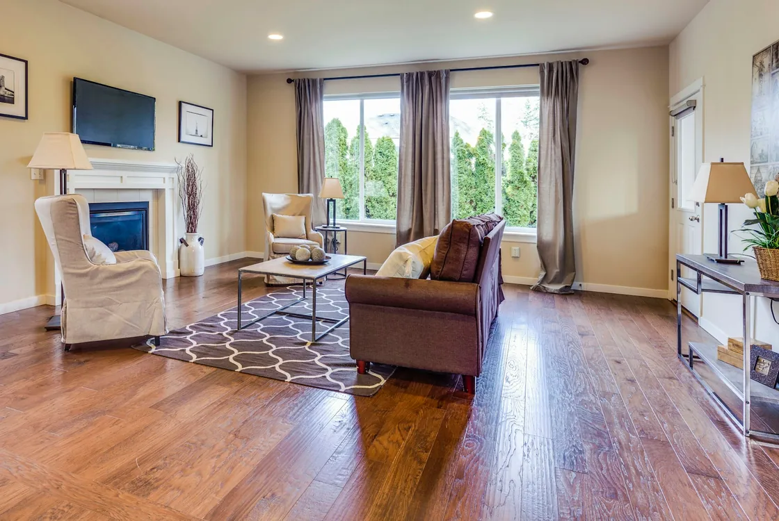 A sitting room with an armchair, sofa, fireplace and large windows