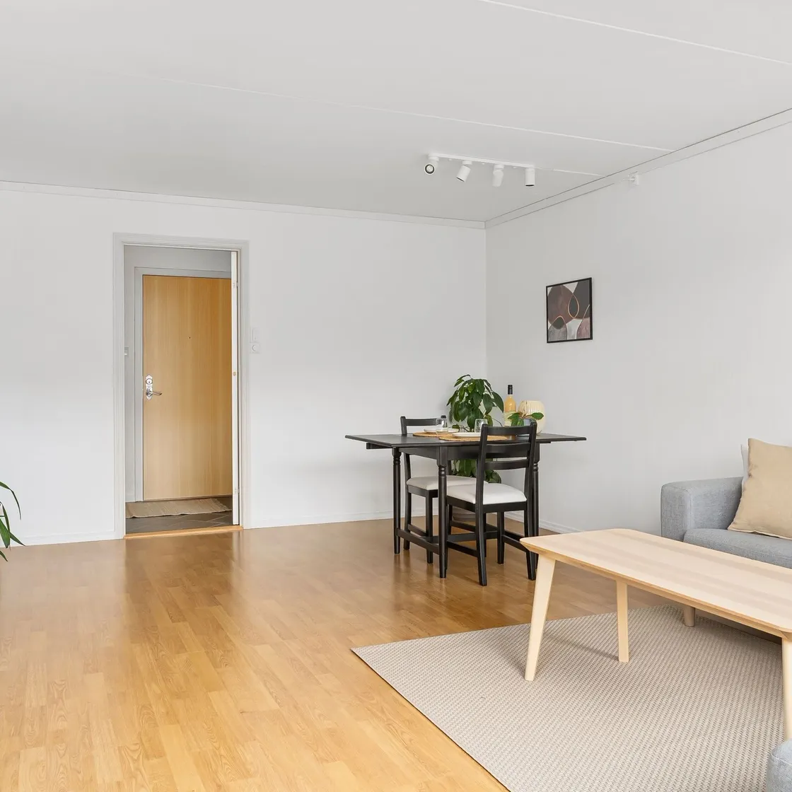 A low pale wooden table beside a grey sofa