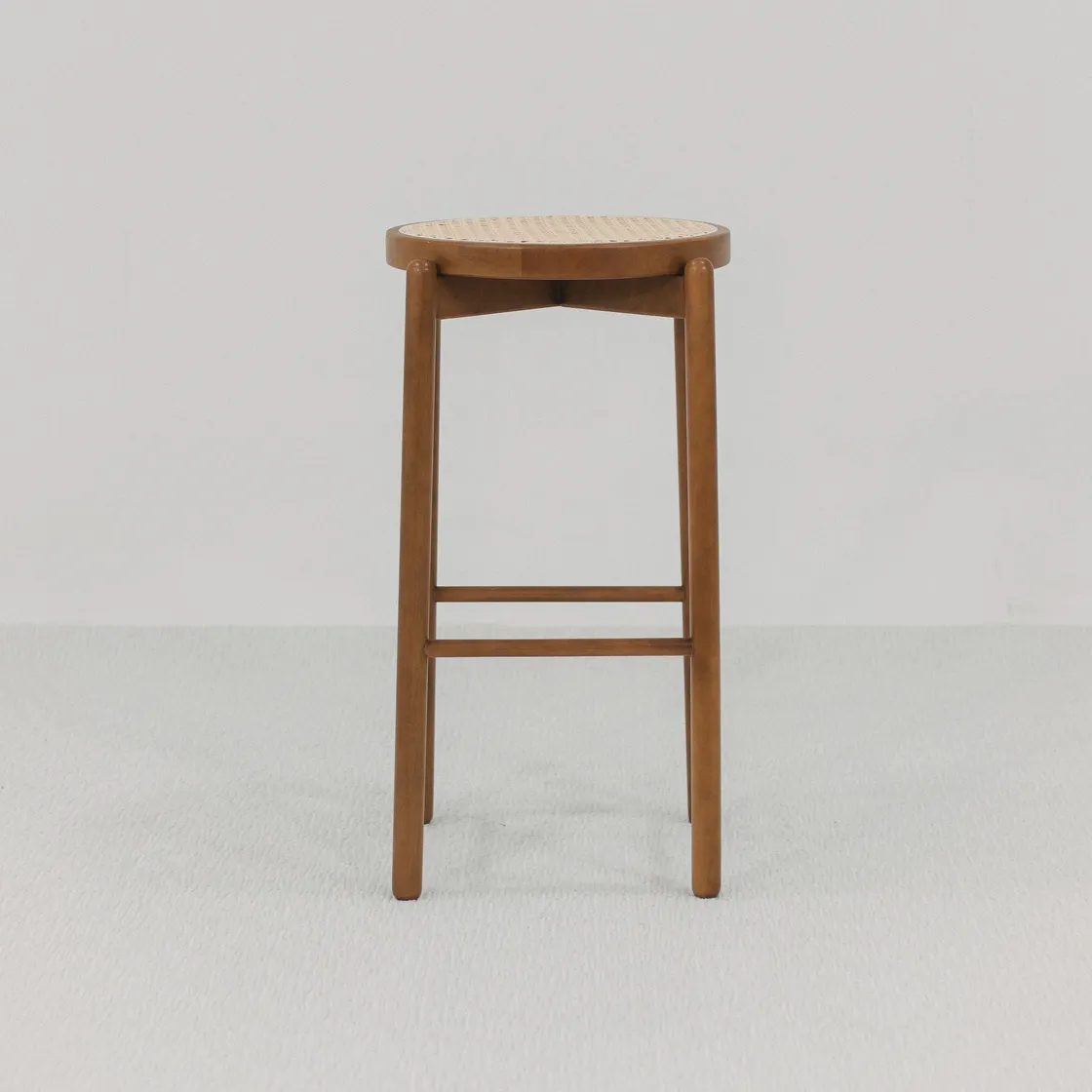 A complete tall wooden stool against a neutral wall