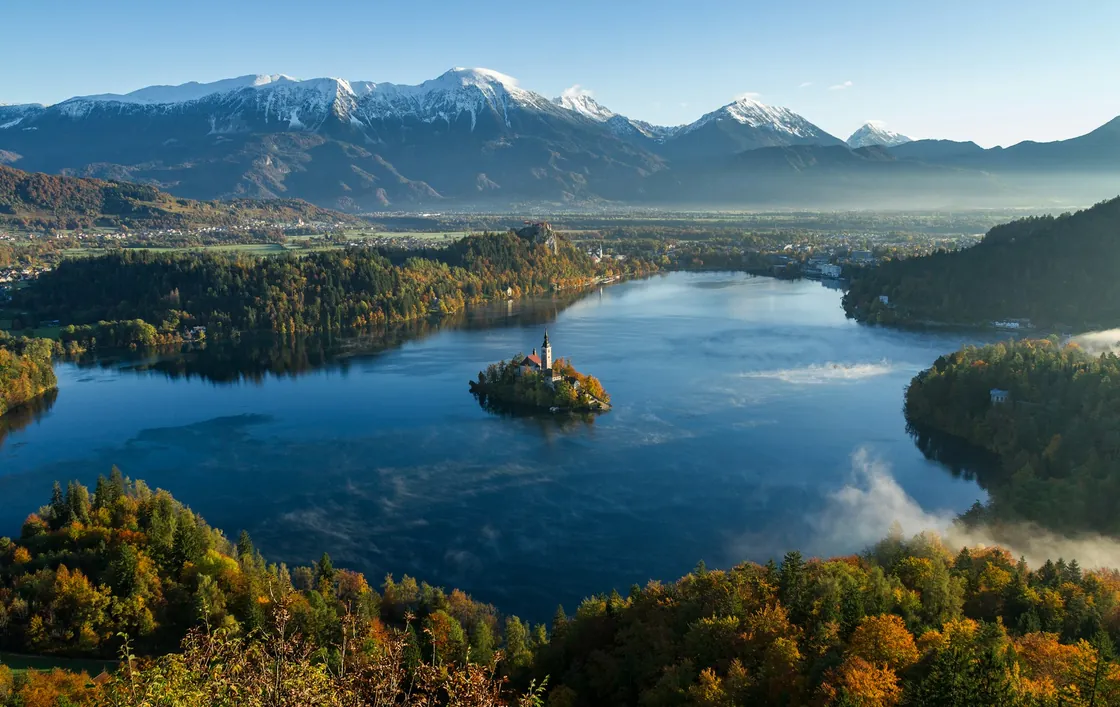 An island church on Lake Bled beneath wooded hills and mountains