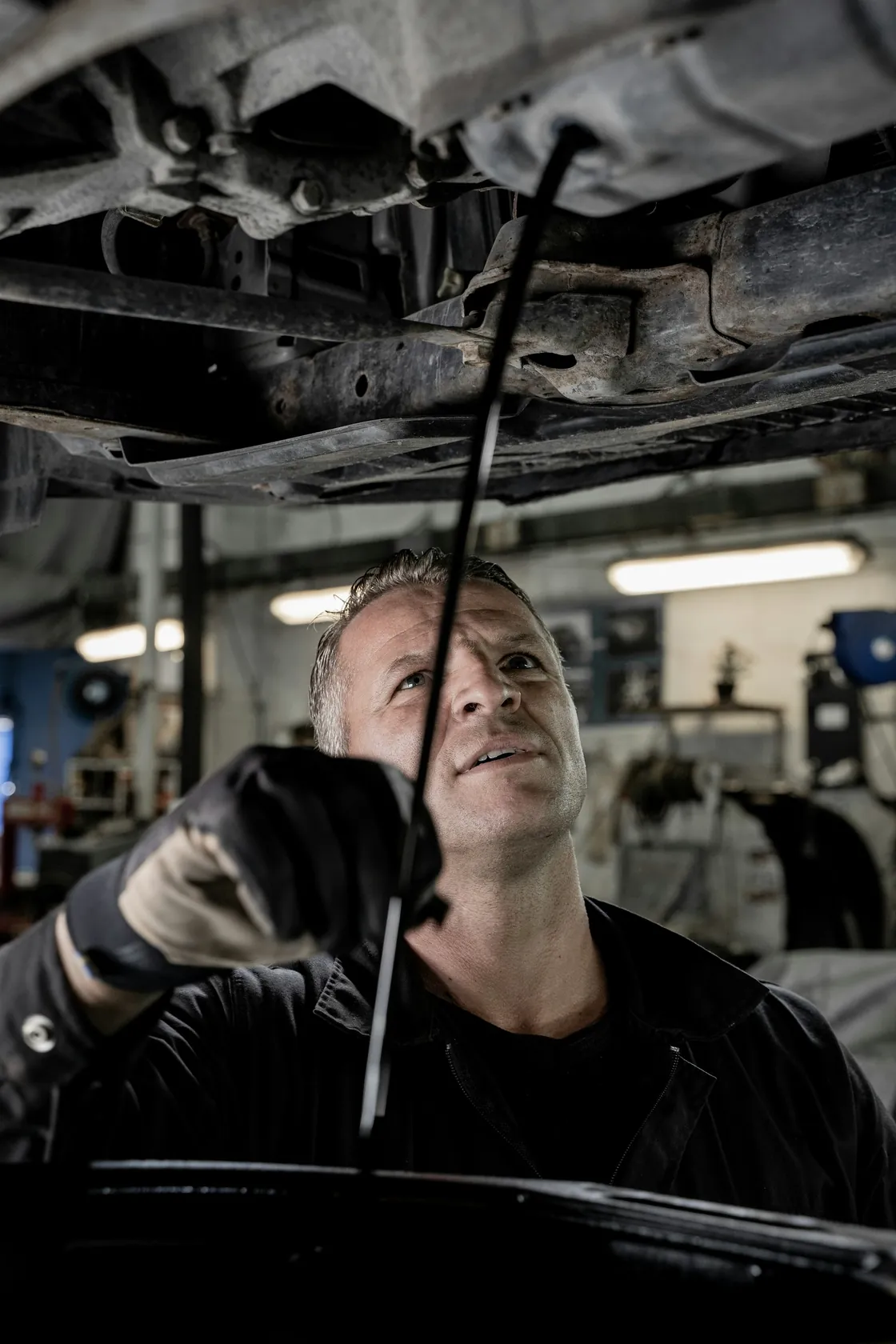 A mechanic working beneath a raised vehicle in a garage