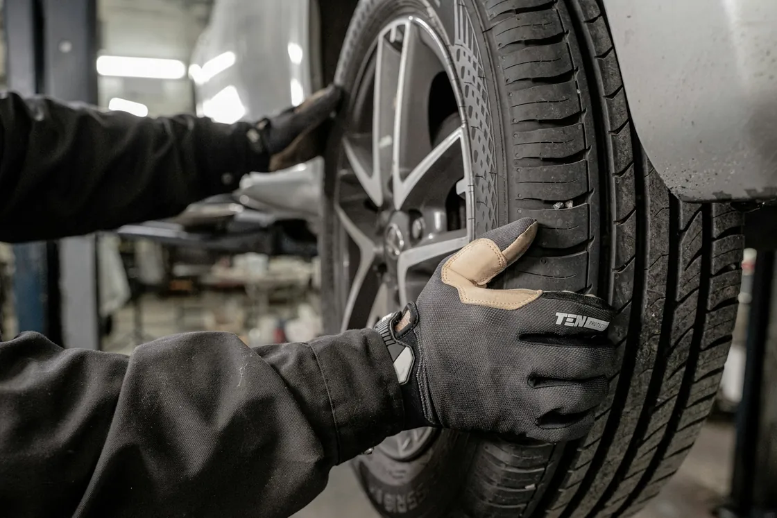 Gloved hands working at a vehicle wheel