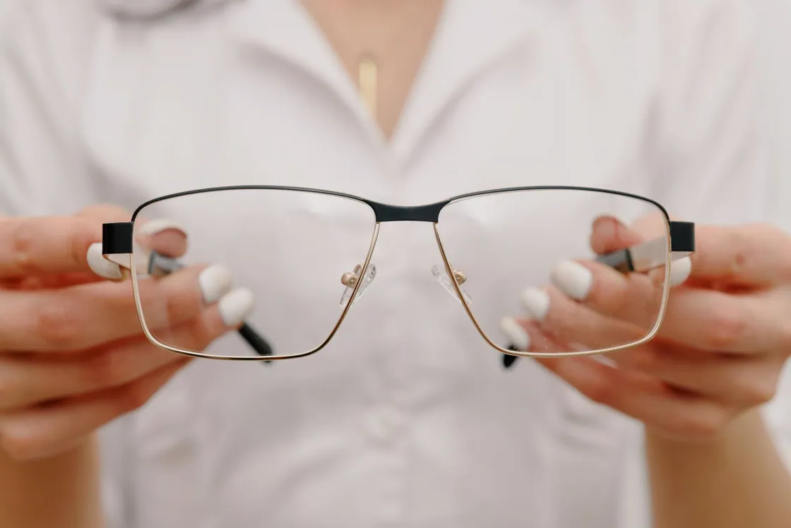 Hands holding a pair of glasses in an optical setting